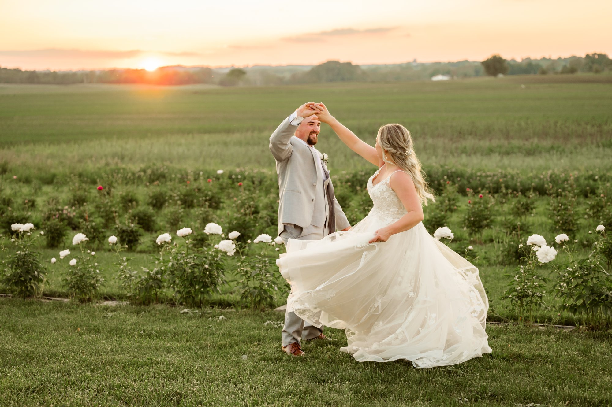 Couple dancing in the field at sunset by the flower rows