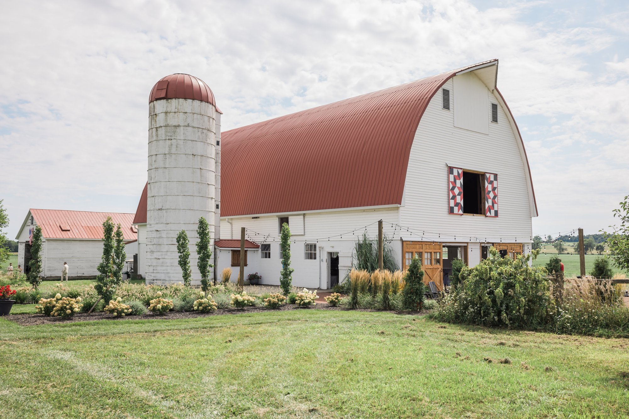 A wide view of the white barn at Wren Farm across the open field.