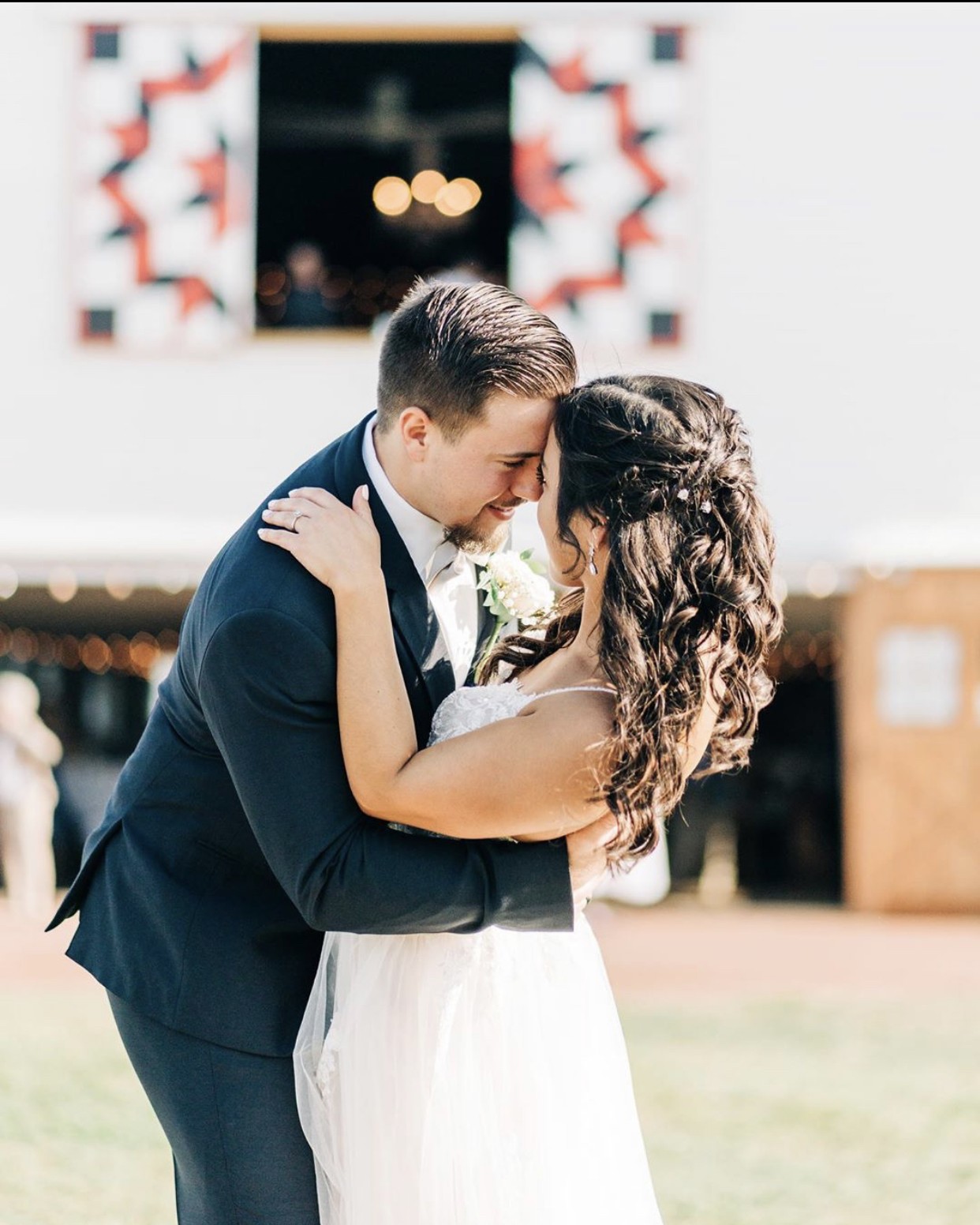 A couple holding each other beneath the barn's quilt block.